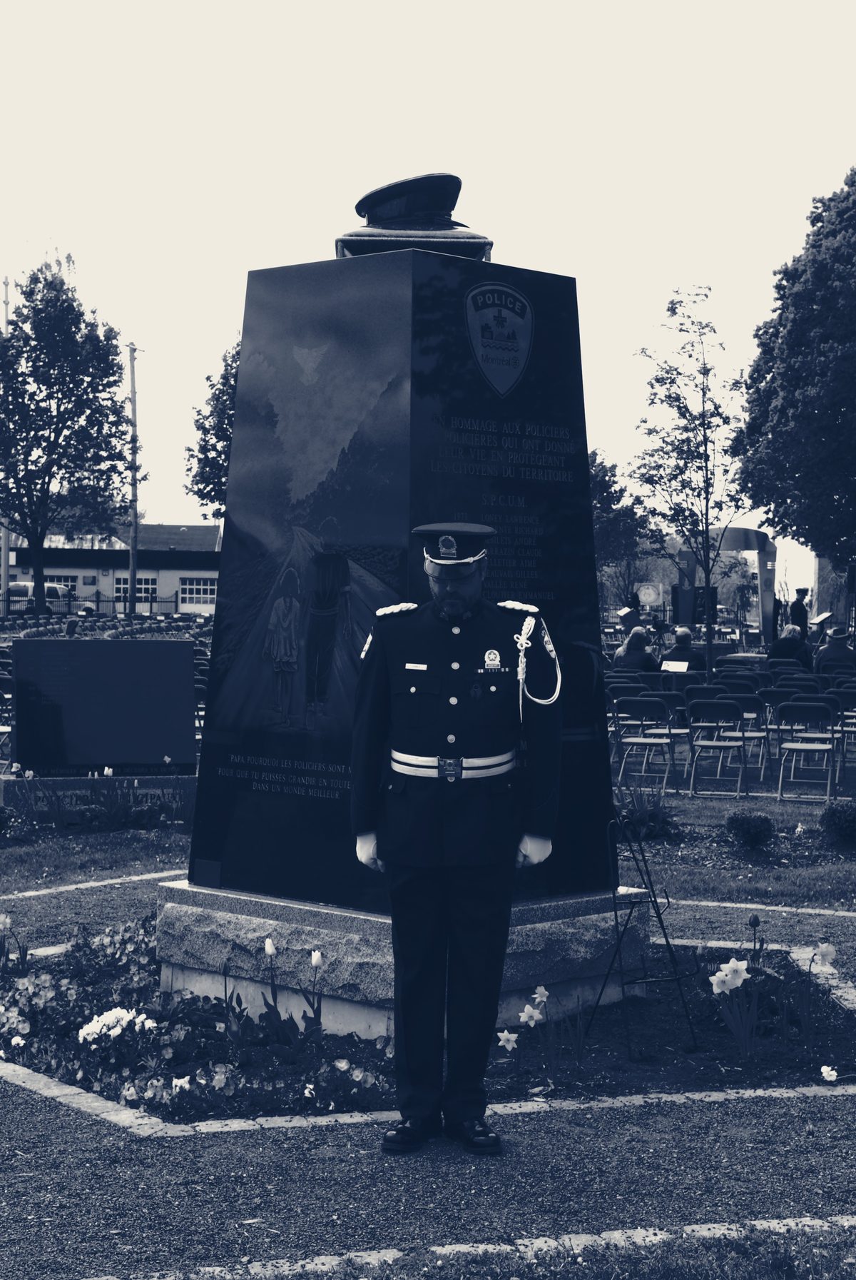 Un policier en grande tenue, tête baissée en signe de recueillement, devant un cénotaphe lors d'une cérémonie d'hommage